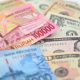 Ilustrasi uang rupiah dan dolar dengan latar grafik nilai tukar.